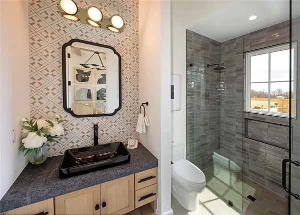 a bathroom with a granite countertop toilet sink and mirror