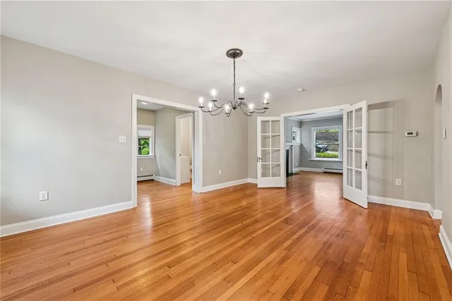 a view of an empty room with wooden floor and a kitchen
