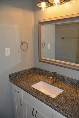 a bathroom with a granite countertop sink and mirror