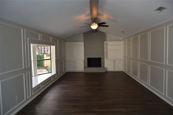 a view of an empty room with wooden floor fireplace and a window