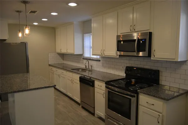 a kitchen with stainless steel appliances granite countertop a stove a sink and a microwave
