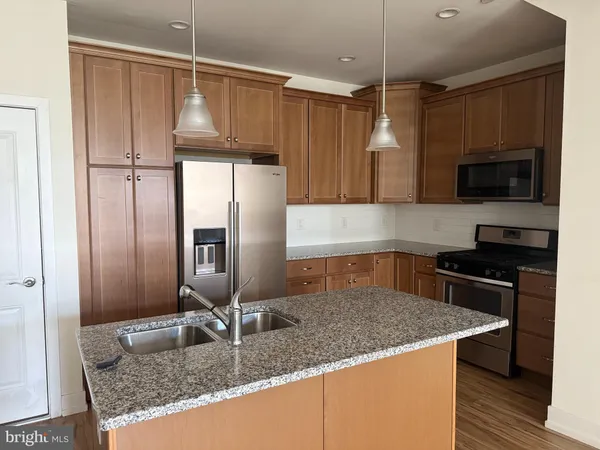 a kitchen with kitchen island granite countertop a sink stainless steel appliances and cabinets