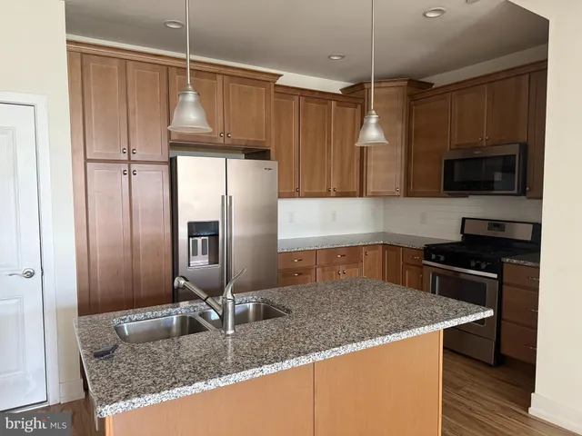 a kitchen with kitchen island granite countertop a sink stainless steel appliances and cabinets