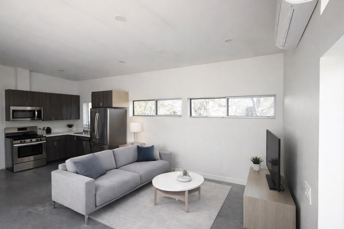 1155 Perry Road, Unit B Austin, TX 78721 - Photo 3 of 7 Living room with finished concrete floors and an AC wall unit