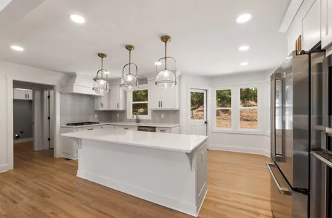 a large kitchen with stainless steel appliances kitchen island granite countertop a stove a refrigerator a oven and a sink with large countertops