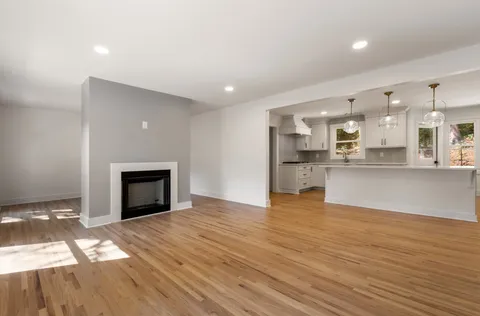 a view of kitchen and empty room with wooden floor
