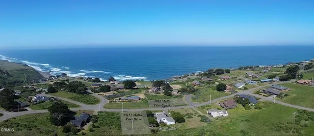 an aerial view of ocean and residential houses with outdoor space