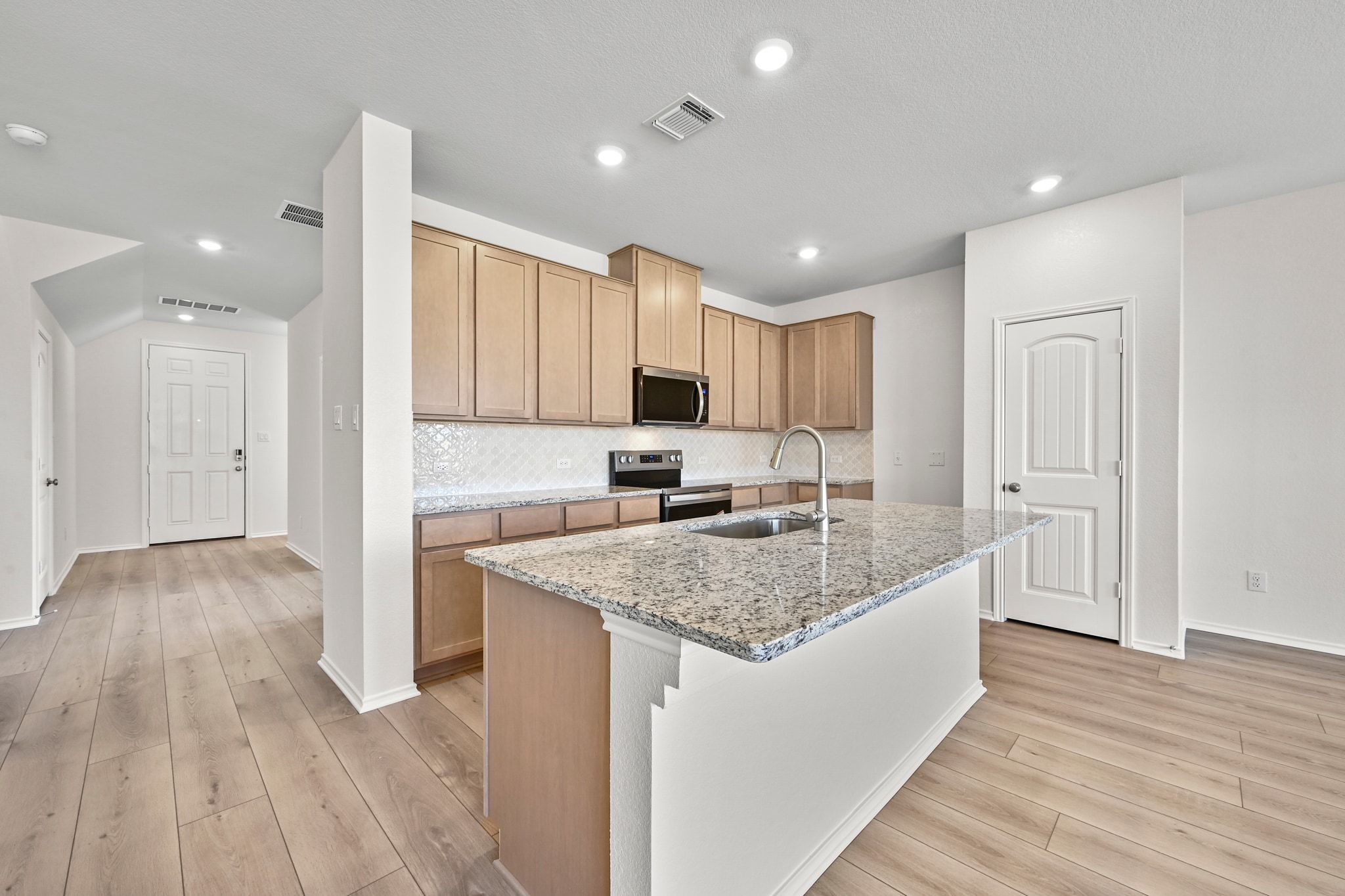 15004 Garrano Way Manor, TX 78653 - Photo 8 of 34 a large kitchen with stainless steel appliances granite countertop a lot of counter space and wooden floors