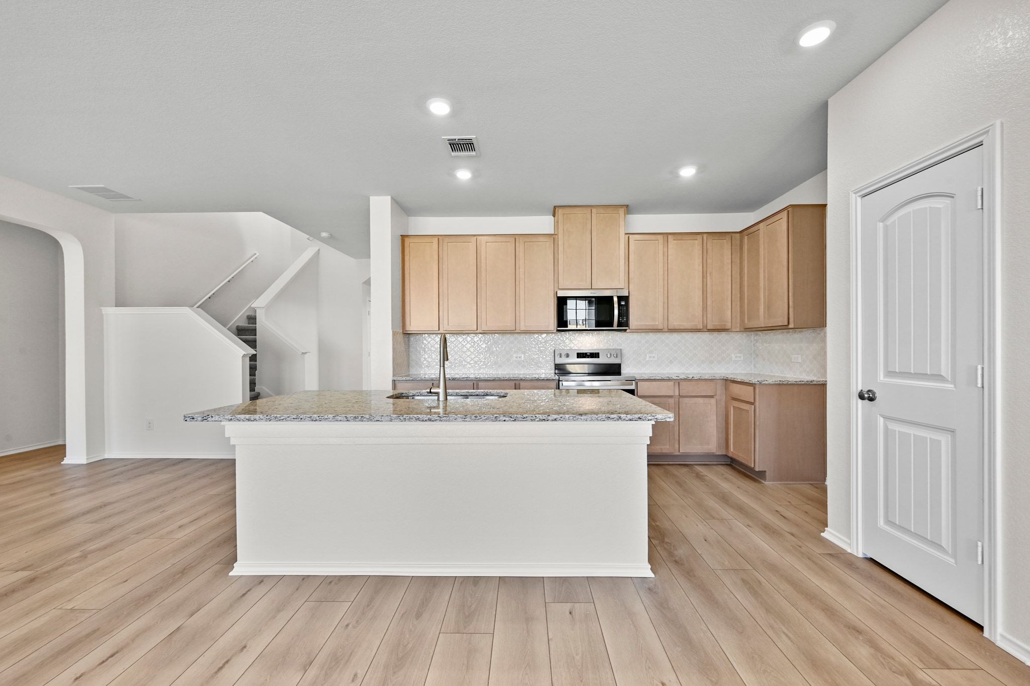 15004 Garrano Way Manor, TX 78653 - Photo 9 of 34 a large kitchen with stainless steel appliances a large counter top a sink and a stove