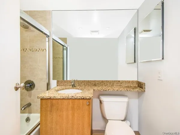 a bathroom with a granite countertop toilet sink and mirror