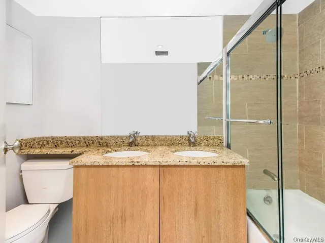 a bathroom with a granite countertop sink a toilet and shower
