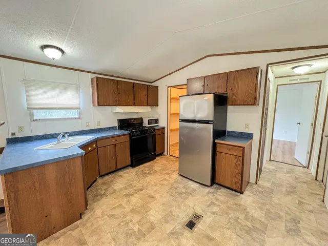 a kitchen with a refrigerator sink and wooden cabinets