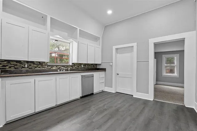 a kitchen with granite countertop a stove and white cabinets