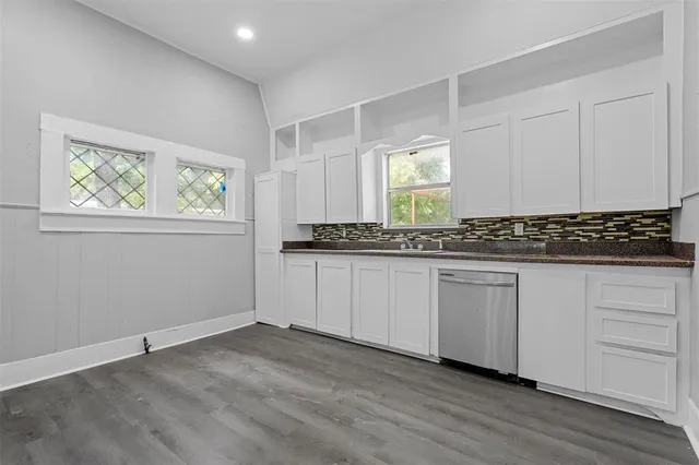 a view of a kitchen with granite countertop white cabinets and window