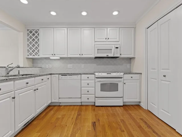 a kitchen with granite countertop white cabinets and white appliances