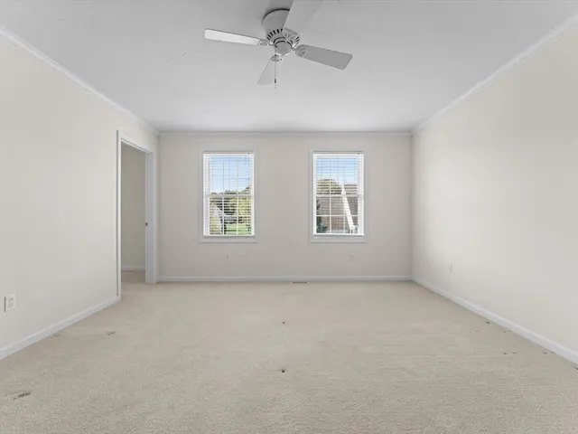 an empty room with windows and ceiling fan