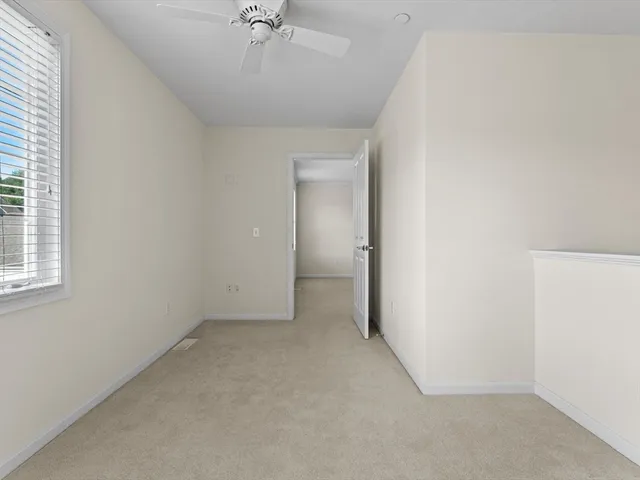 an empty room with a ceiling fan and a window
