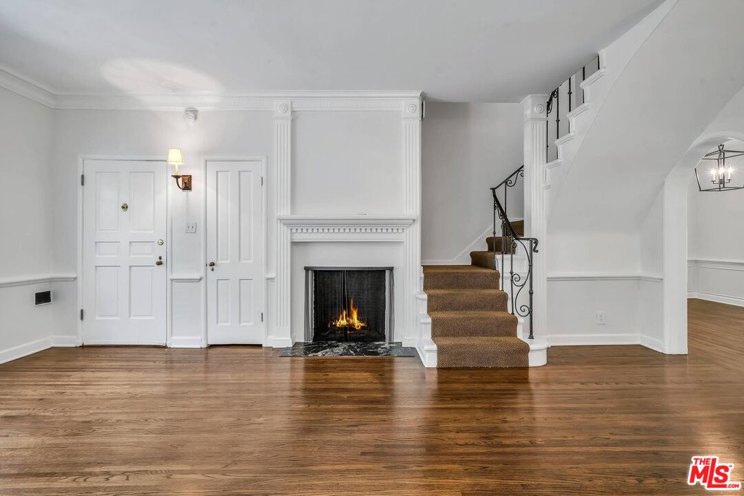 360 South Roxbury Drive Beverly Hills, CA 90212 - Photo 3 of 30 a view of a livingroom with wooden floor fireplace and staircase