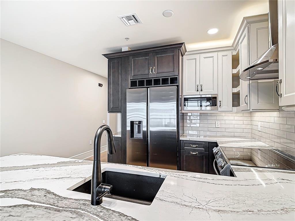 2745 First Street, Unit 111 Fort Myers, FL 33916 - Photo 14 of 79 a kitchen with granite countertop a refrigerator a sink and wooden cabinets