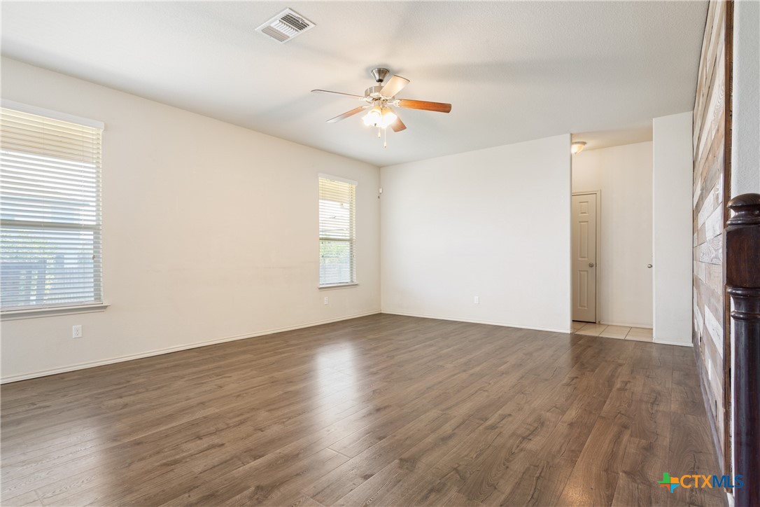 231 Druse Lane Jarrell, TX 76537 - Photo 4 of 38 an empty room with wooden floor a ceiling fan and windows