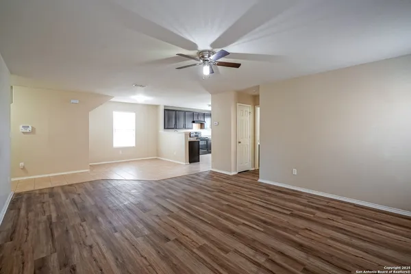 a view of an empty room with window and wooden floor
