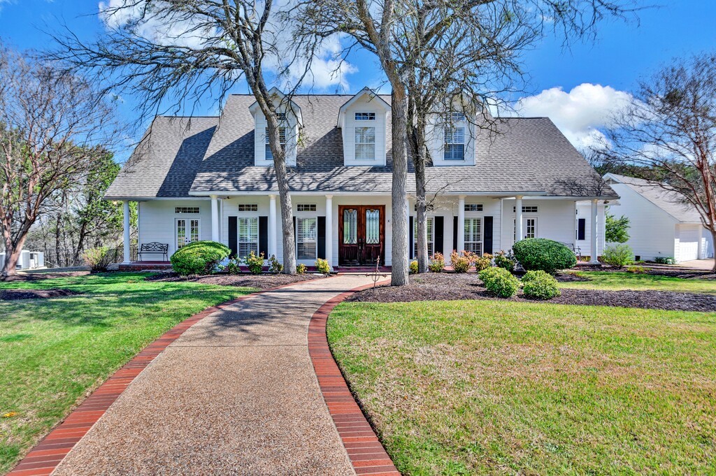 a view of a house with garden and a tree in front of it