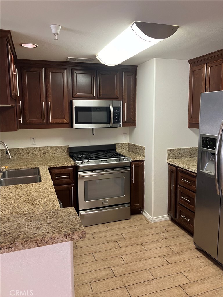11925 Kling Street, Unit 111 Valley Village, CA 91607 - Photo 12 of 16 a kitchen with granite countertop a stove and a microwave