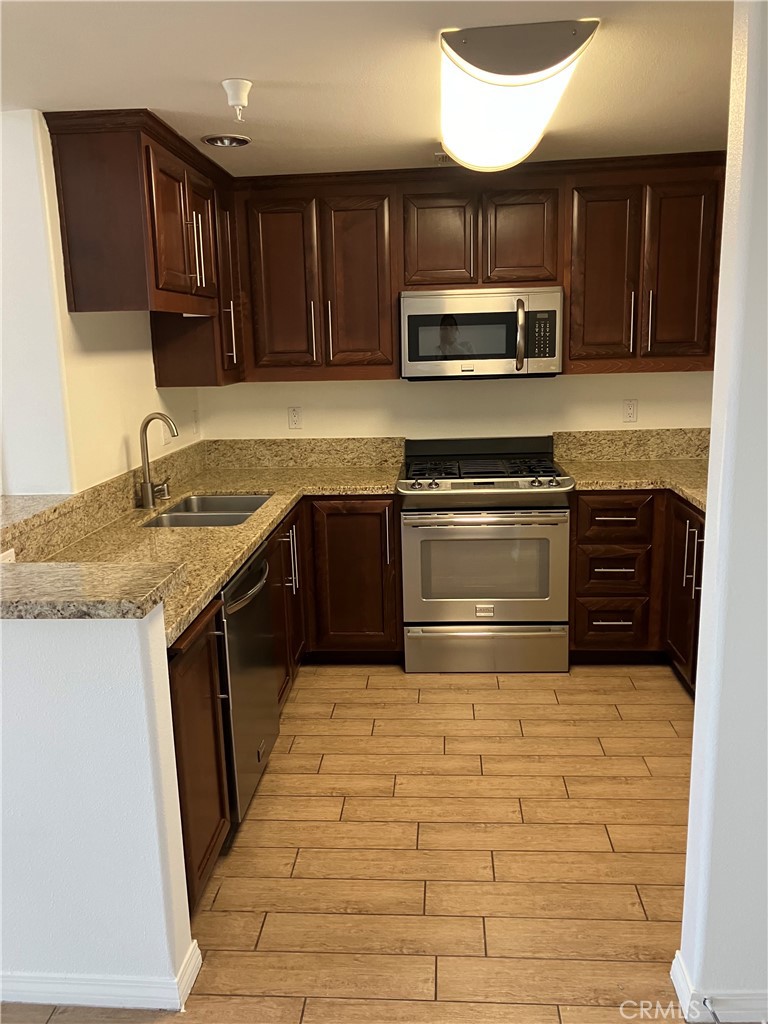 11925 Kling Street, Unit 111 Valley Village, CA 91607 - Photo 13 of 16 a kitchen with stainless steel appliances granite countertop a stove sink and cabinets