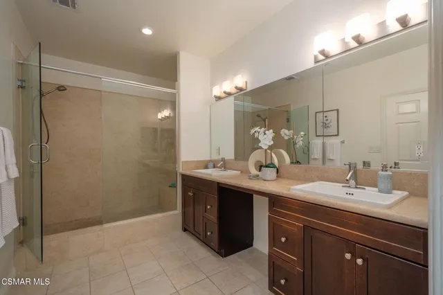 a bathroom with a double vanity sink mirror and shower