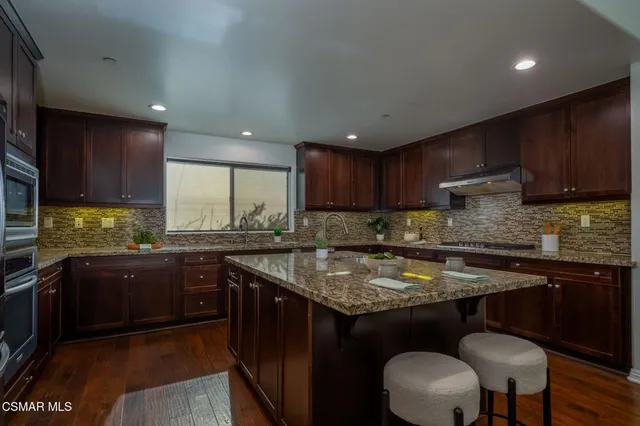a kitchen with kitchen island granite countertop wooden cabinets dining table and chairs