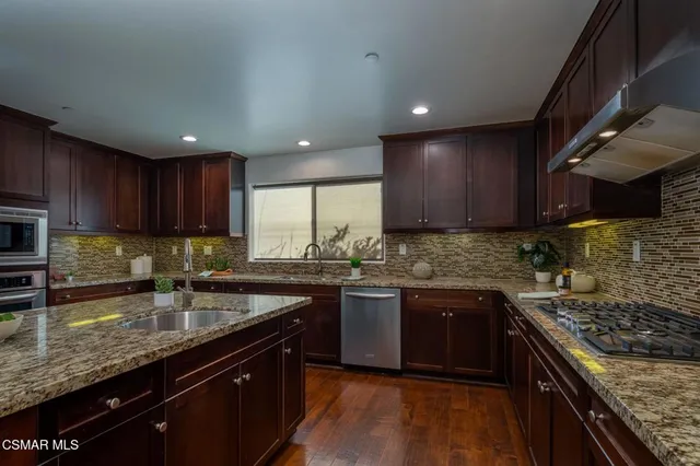 a kitchen with stainless steel appliances granite countertop sink stove top oven and cabinets