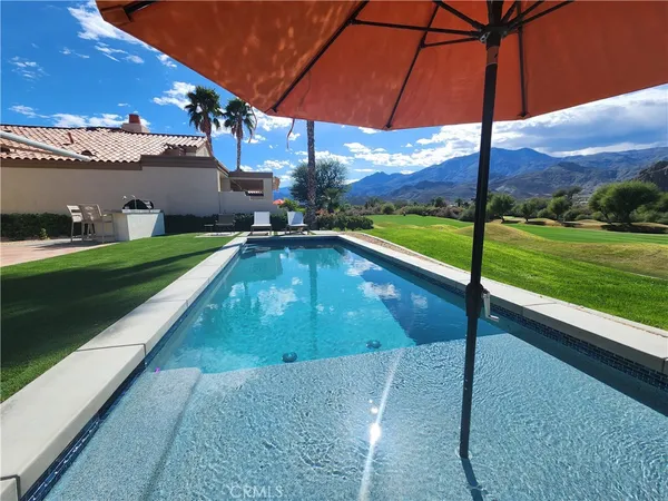 a front view of a house with a garden and swimming pool