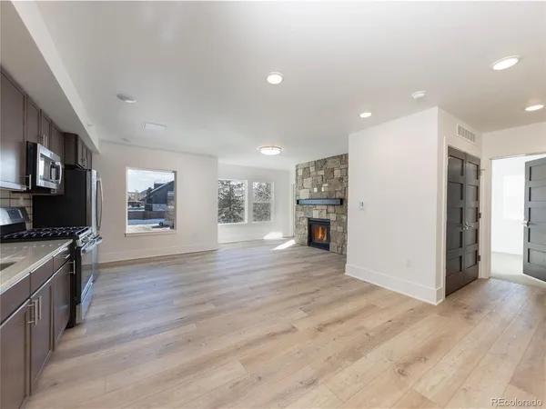 an empty room with wooden floor and a kitchen