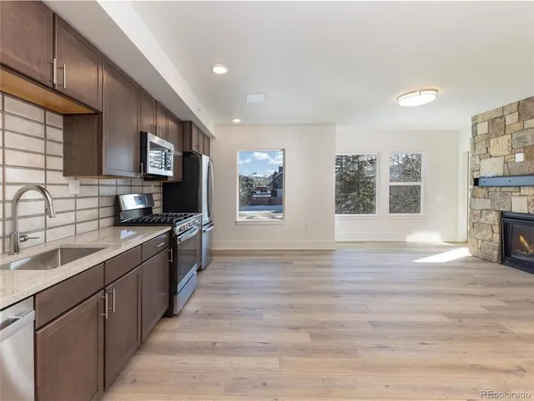 a large kitchen with stainless steel appliances granite countertop a sink and dishwasher a stove top oven with wooden floor