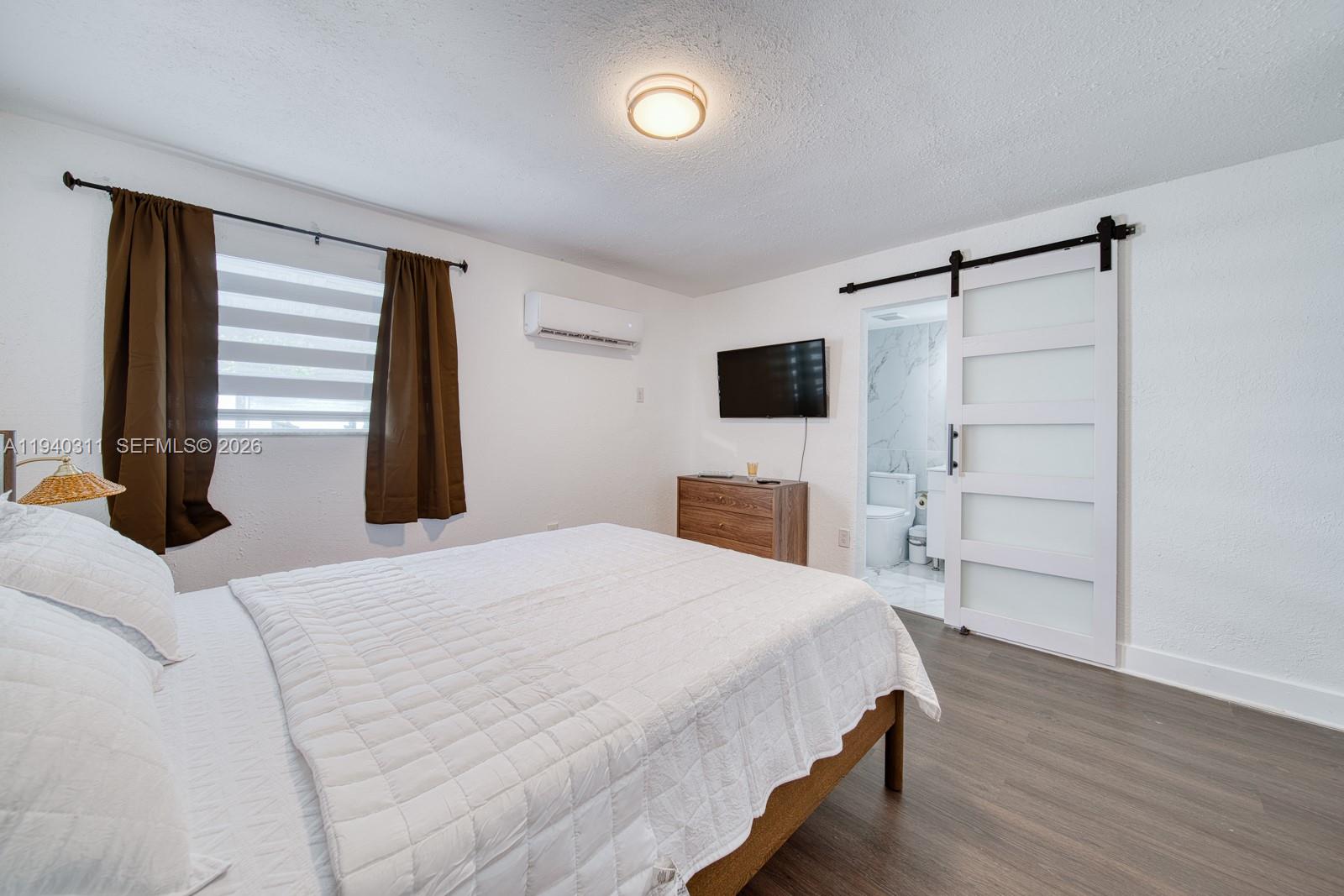 2741 Southwest 67th Avenue, Unit 1 Miami, FL 33155 - Photo 18 of 24 a bedroom with a bed and a flat tv screen on wall