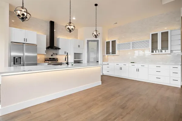 a large kitchen with kitchen island a stove a sink a center island and wooden floor