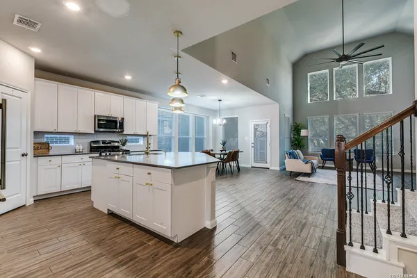 a kitchen with stainless steel appliances granite countertop wooden floors a stove and a refrigerator