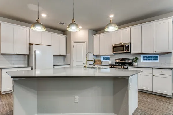a kitchen with kitchen island granite countertop a sink a counter space stainless steel appliances and cabinets