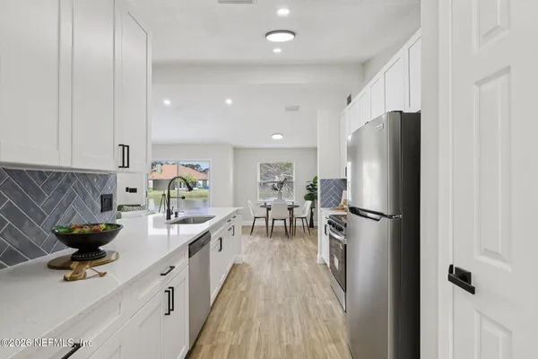 a kitchen with stainless steel appliances a refrigerator a sink a stove and white cabinets