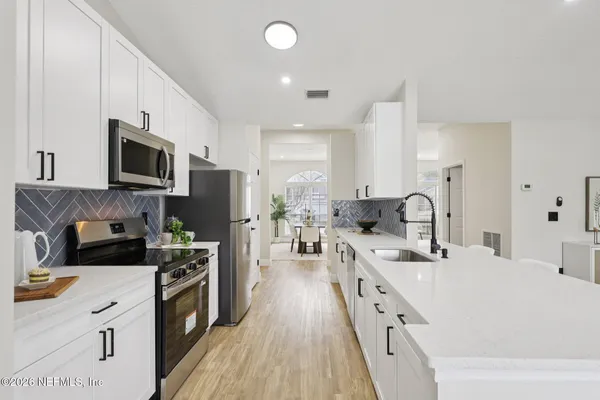 a large white kitchen with stainless steel appliances granite countertop lots of counter top space a sink and dishwasher