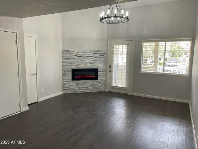 an empty room with wooden floor fireplace and chandelier