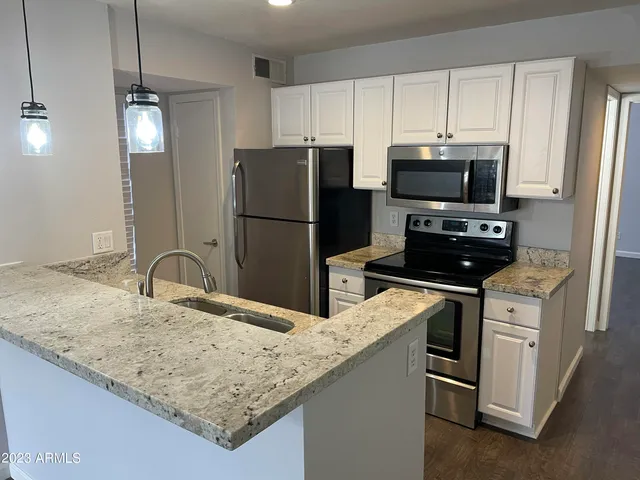 a kitchen with stainless steel appliances granite countertop a refrigerator a stove a sink a microwave and island