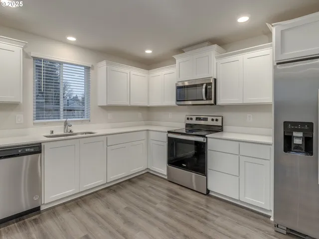 a kitchen with granite countertop white cabinets and stainless steel appliances