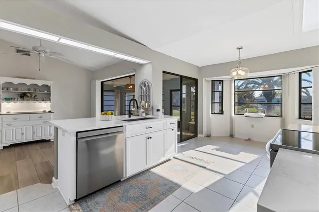 a large white kitchen with stainless steel appliances kitchen island granite countertop a refrigerator a stove a sink dishwasher and white cabinets with wooden floor