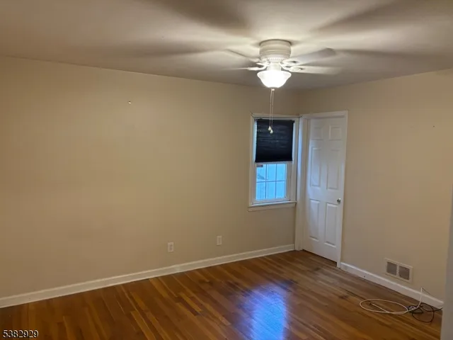 a view of wooden floor and a chandelier fan in a room
