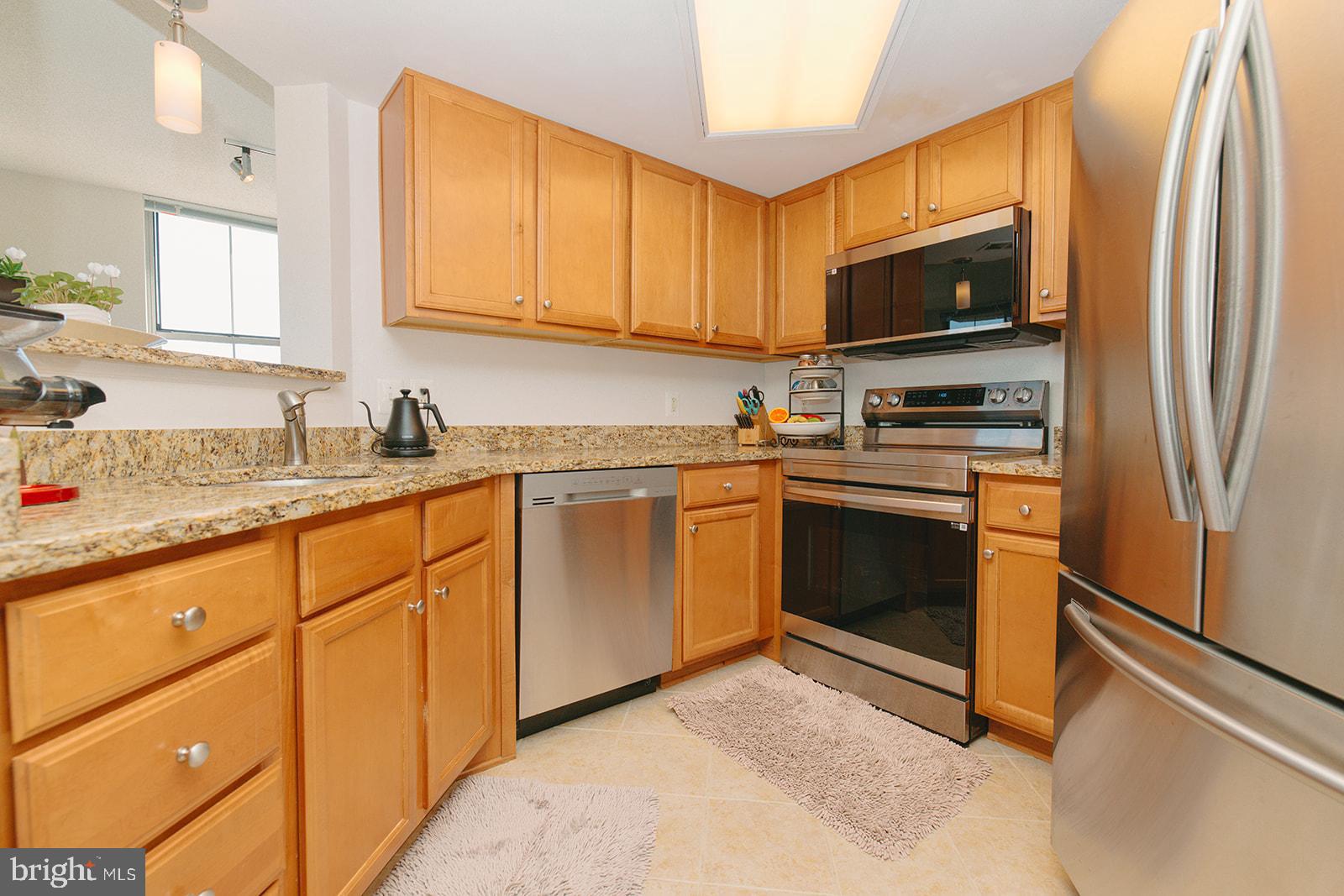 11800 Sunset Hills Road, Unit 506 Reston, VA 20190 - Photo 11 of 30 a kitchen with stainless steel appliances granite countertop a stove a sink and a refrigerator