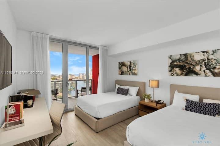 2602 East Hallandale Beach Boulevard, Unit R2006 Hallandale Beach, FL 33009 - Photo 12 of 24 a bedroom with two beds and a large window