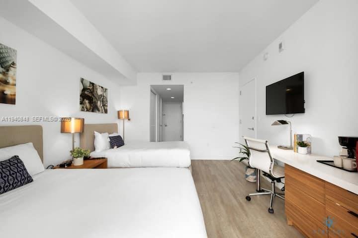 2602 East Hallandale Beach Boulevard, Unit R2006 Hallandale Beach, FL 33009 - Photo 13 of 24 a bedroom with a bed a flat screen tv and a couch