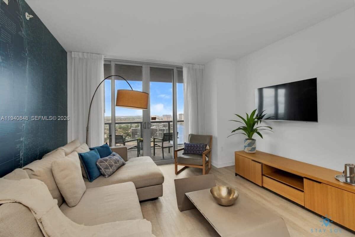 2602 East Hallandale Beach Boulevard, Unit R2006 Hallandale Beach, FL 33009 - Photo 22 of 24 a living room with furniture and a flat screen tv