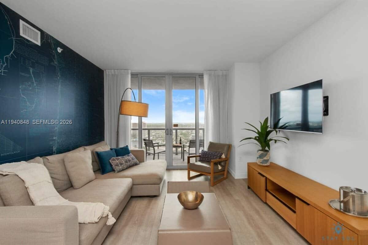 2602 East Hallandale Beach Boulevard, Unit R2006 Hallandale Beach, FL 33009 - Photo 8 of 24 a living room with furniture and a potted plant